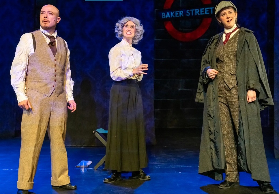 A man in a tie and beige vest, a woman in a white blouse and dark gray skit, and a woman in a deerstalker and a long gray coat.
