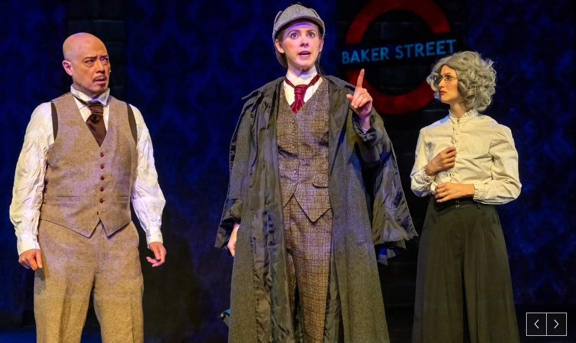 The man in the tie a beige vest, a woman wearing a deerstalker and a long coat, and a woman wearing a gray blouse and dark gray skirt.