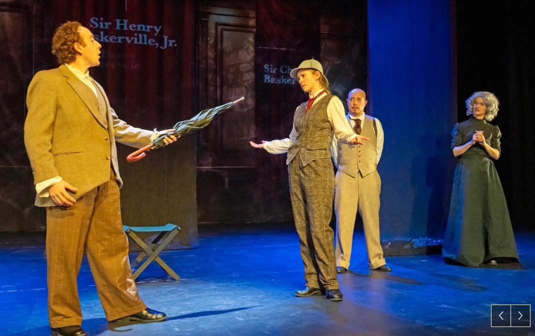 A man in a light brown suit pointing an umbrellas at a woman in a deerstalker and brown plaid vest and pants.